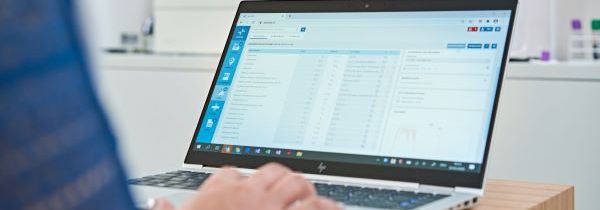 Assistante médicale qui utilise un ordinateur portable avec le logiciel Axenita dans un laboratoire de cabinet médical.